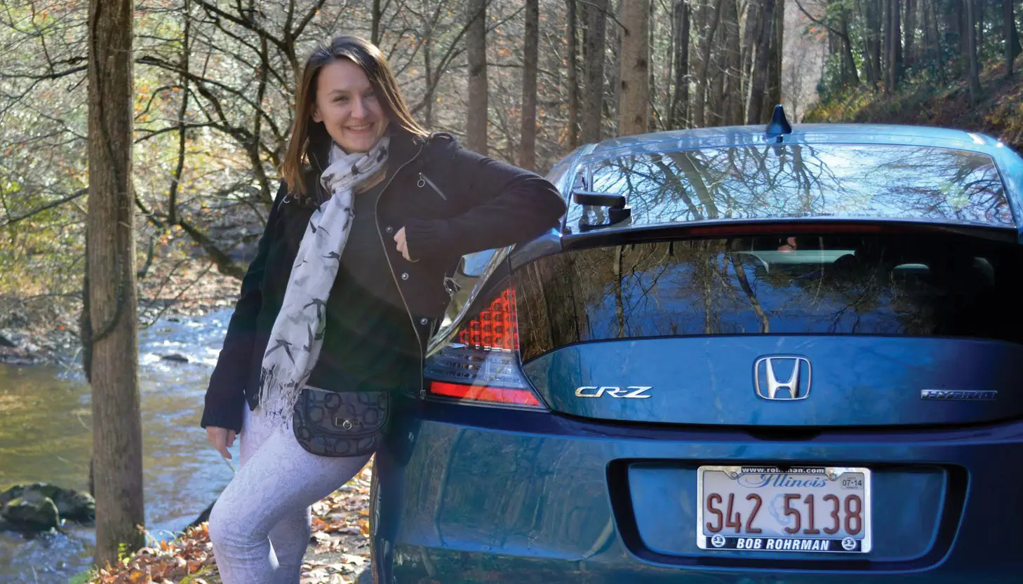 Jessica leaning next to a blue car
