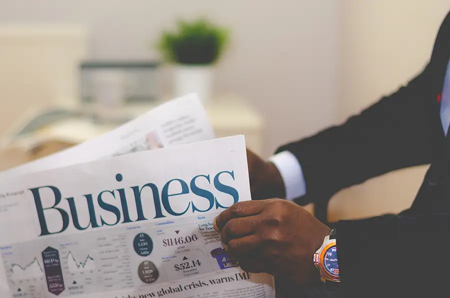 A man browses the business section of a newspaper.