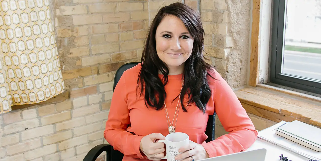 Kim Bode smiles at the camera while drinking coffee in the 8THIRTYFOUR office.