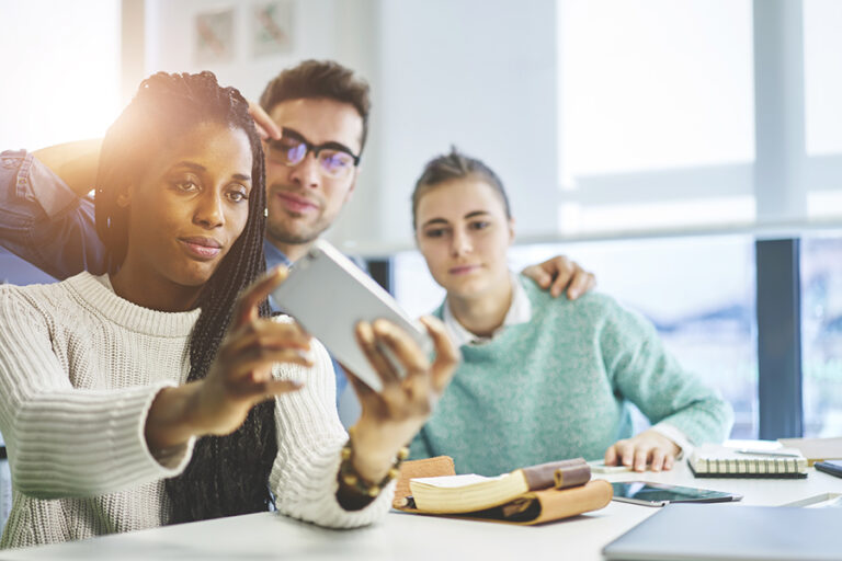 Multiple coworkers pose for a selfie at work.