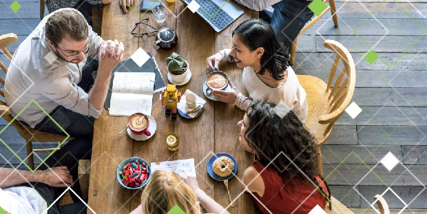 Several people sit around a table while discussing business and enjoying lunch.