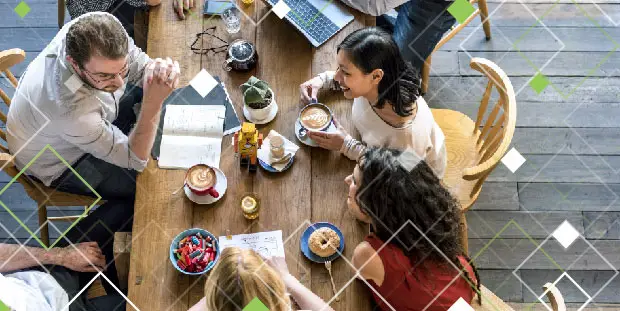 Several people sit around a table while discussing business and enjoying lunch.