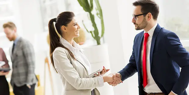 A man and woman shake hands at a business meeting.