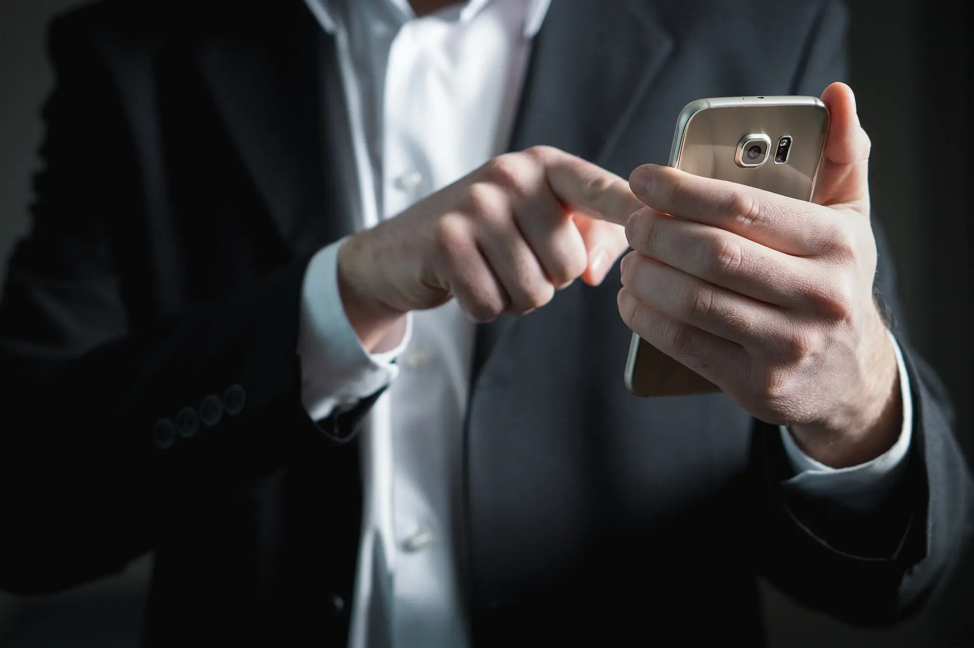 A man in a suit uses a smartphone