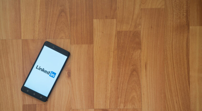 A phone displays the LinkedIn log in screen