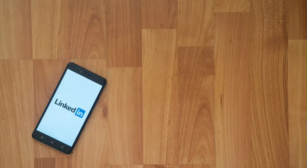 A phone displays the LinkedIn log in screen
