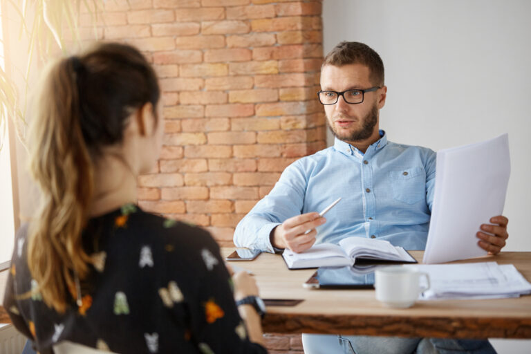 An interviewer sits across from an interviewee at a coffee shop