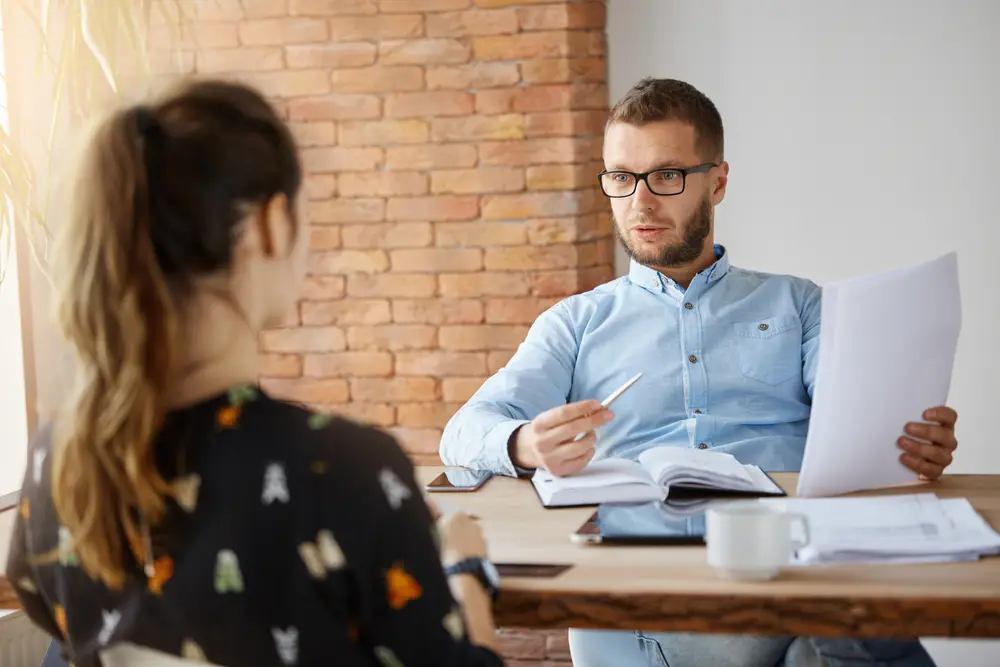 An interviewer sits across from an interviewee at a coffee shop