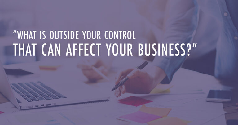 A person leans over a table covered in papers with text that reads, "What is outside your control that can affect your business?"