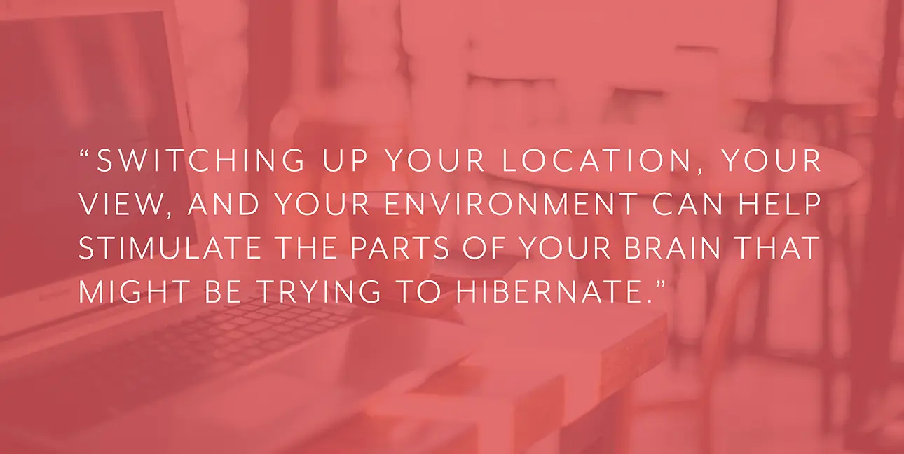 A laptop in a coffee shop with red overlay and text that reads, "Switching up your location, your view, and your environment can help stimulate the parts of your brain that might be trying to hibernate."