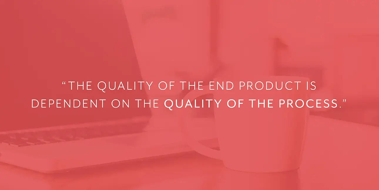 A coffee cup sits next to a laptop with white font that reads, "The quality of the end product is dependent on the quality of the process."