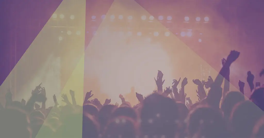 A concert from the pit, including many hands in the air and a smoke effect on stage