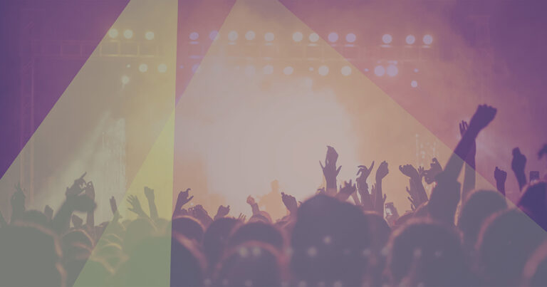 A concert from the pit, including many hands in the air and a smoke effect on stage