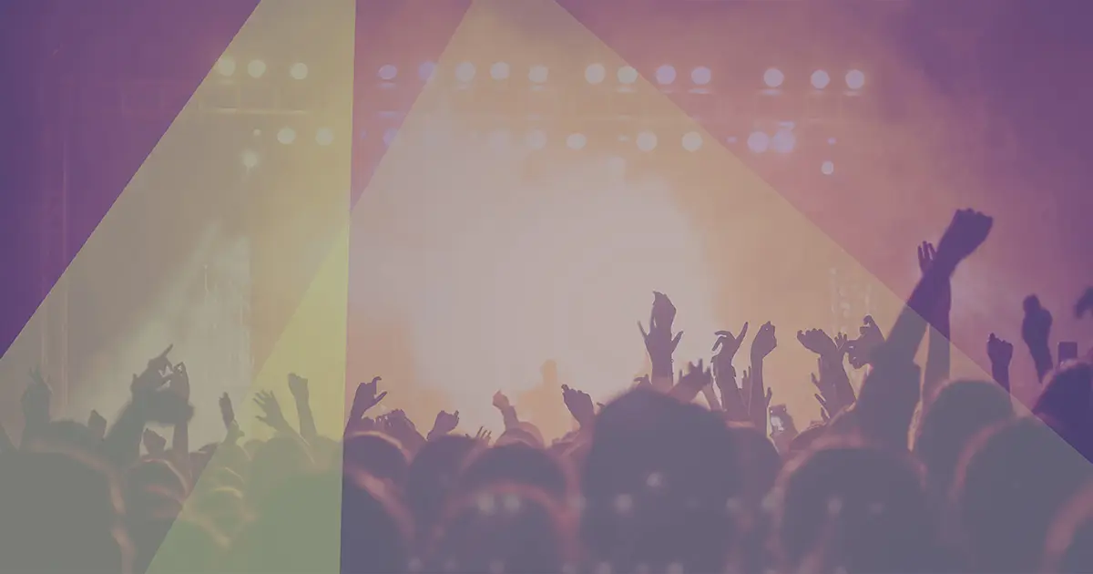 A concert from the pit, including many hands in the air and a smoke effect on stage