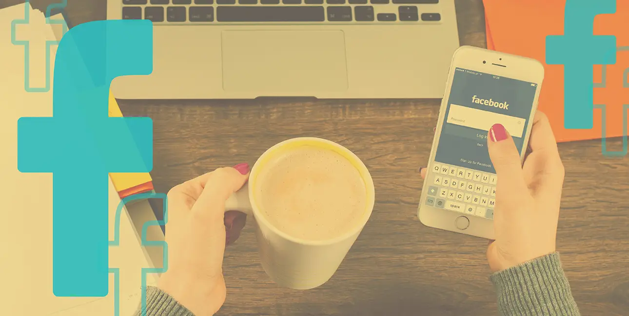 A woman holds an iPhone displaying the Facebook log in screen