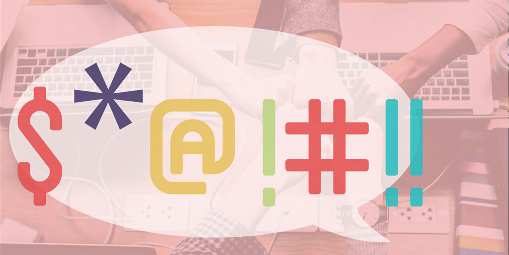 Coworkers fistbump over a table filled with laptops while a cartoon speech bubble indicates a swear word with symbols