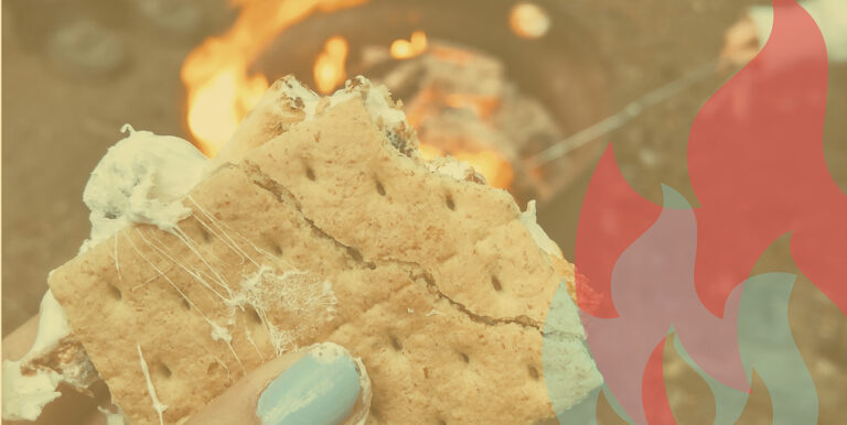 A hand with blue painted nails holds a half-eaten s'more