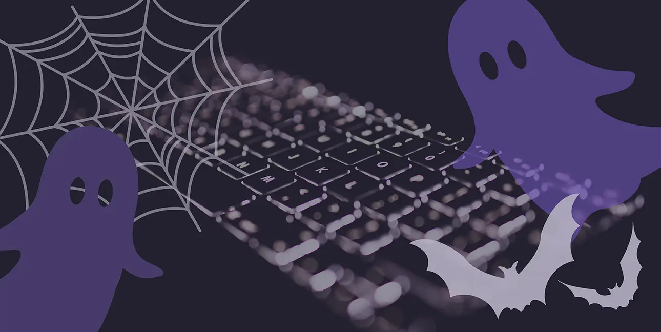 A black keyboard with cartoon ghosts, bats, and a spiderweb superimposed over it.
