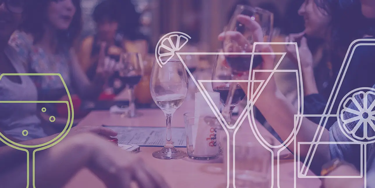 A table with several different drinks on it, surrounded by many people talking and having fun