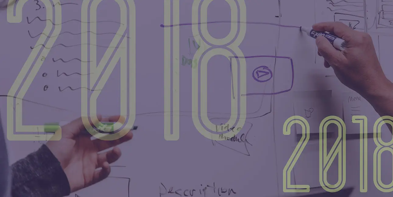 Two hands writing on a whiteboard with "2018" superimposed over them