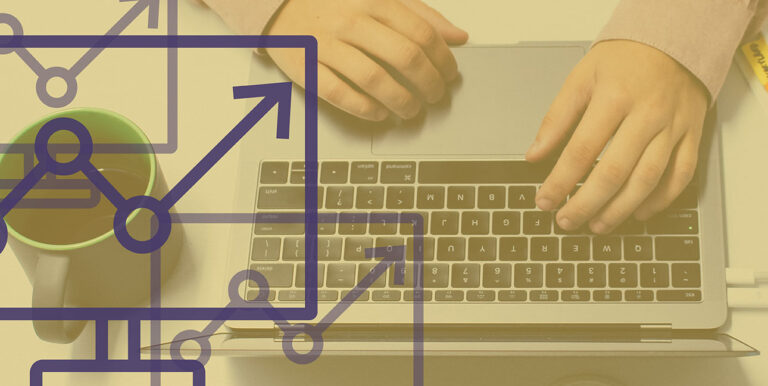 An employee works at a laptop with a coffee mug next to them