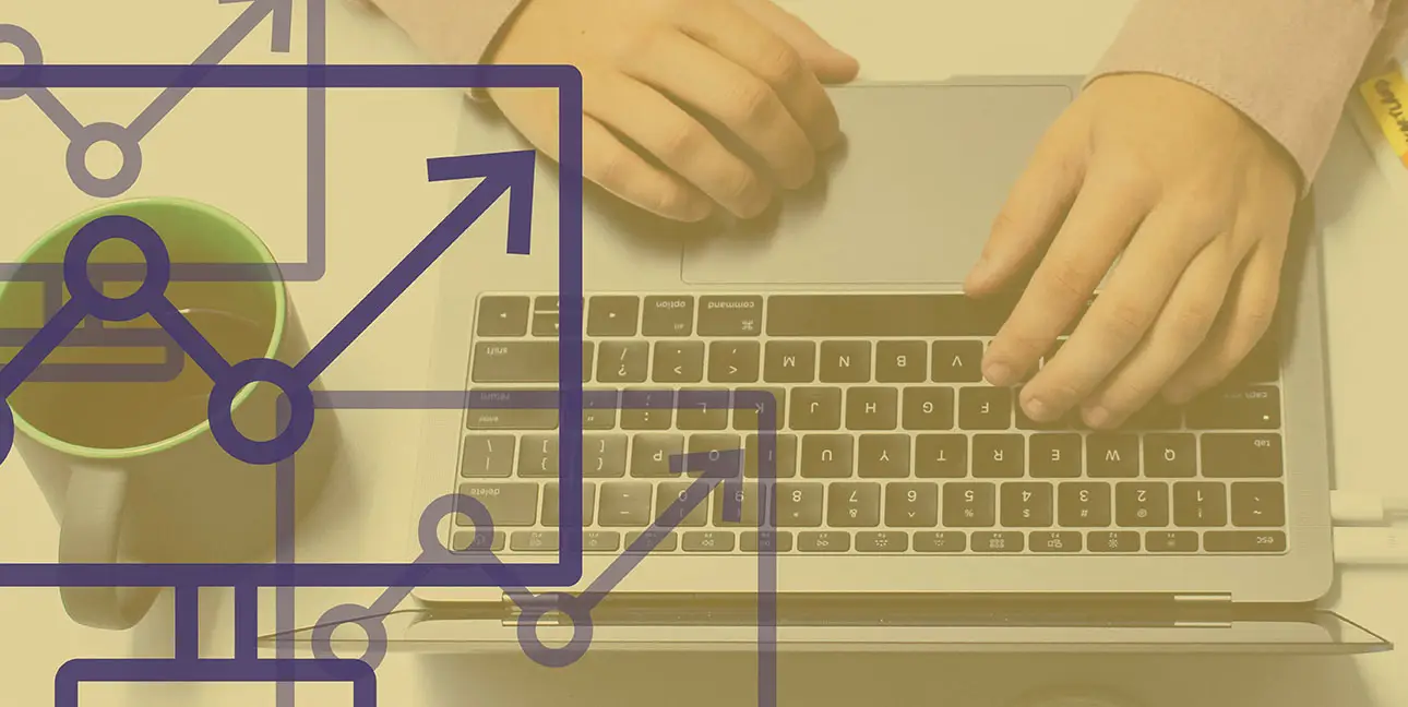 An employee works at a laptop with a coffee mug next to them