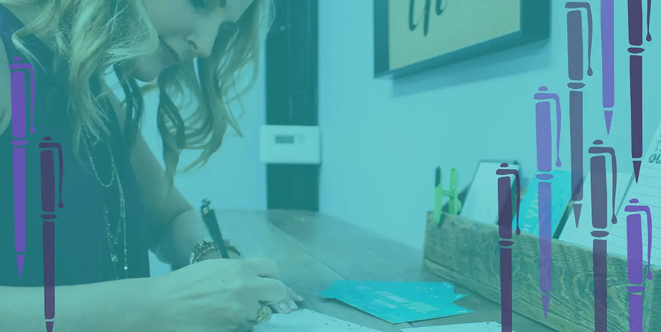 Sarah Abel writes a letter at a standing desk in the 8THIRTYFOUR office