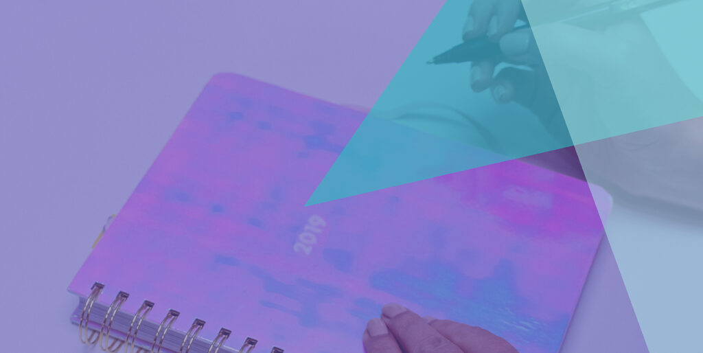 A person with a pen about to write in a journal that says, "2019" on it