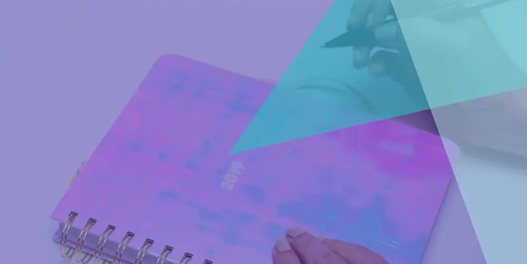 A person with a pen about to write in a journal that says, "2019" on it