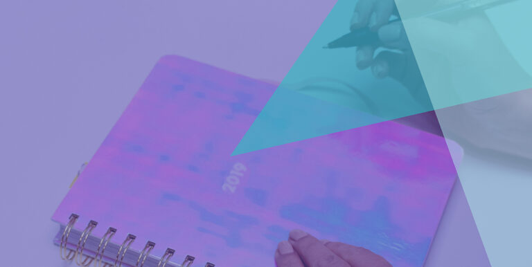 A person with a pen about to write in a journal that says, "2019" on it