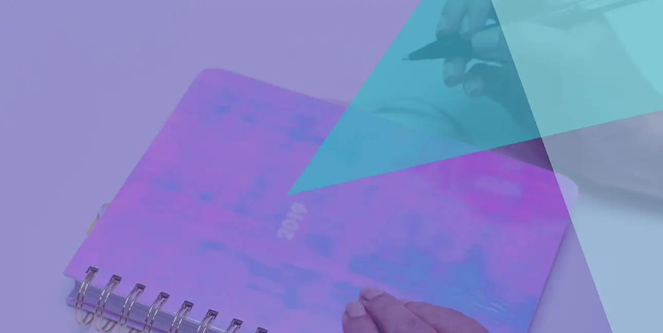 A person with a pen about to write in a journal that says, "2019" on it