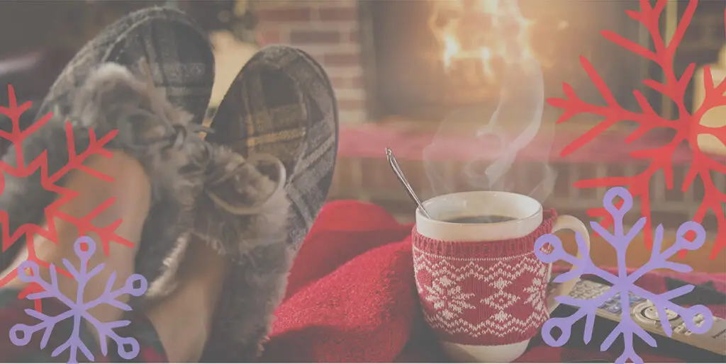 Feet in slippers propped up on an ottoman in front of a fireplace