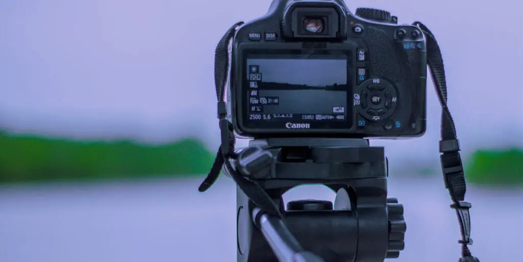 A camera on a tripod films activity over a lake.