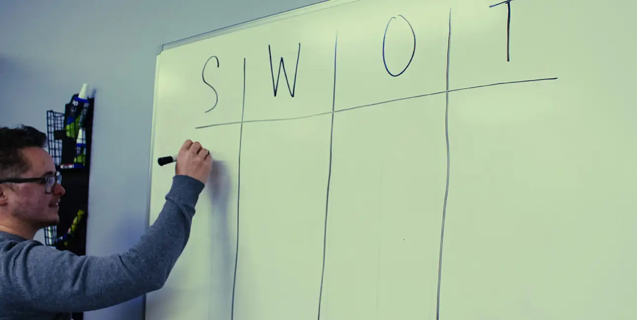 Kayden Grinwis does a SWOT analysis on a large piece of paper in the 8THIRTYFOUR office.