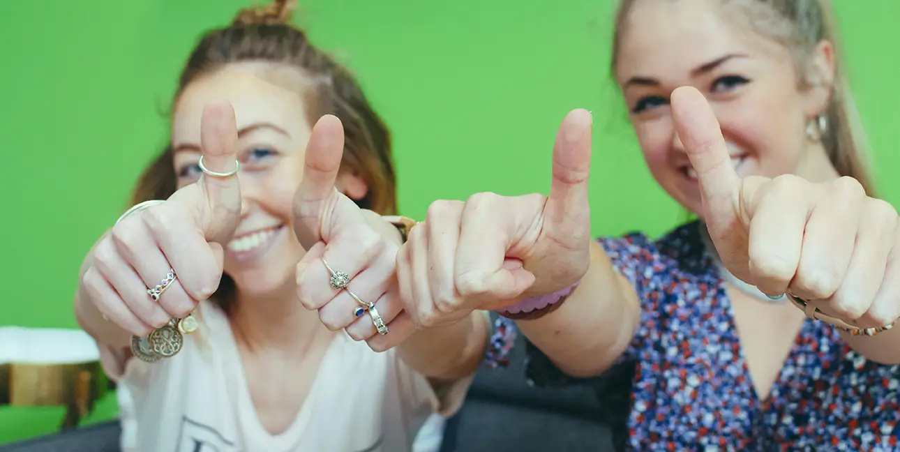Communications Associate Morgan and Digital Associate Erica flash the camera a positive thumbs up.