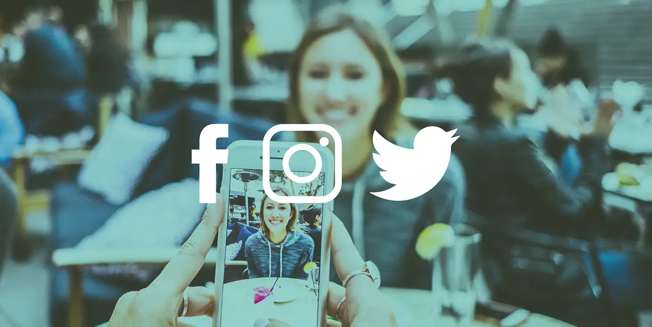 A photo of someone taking a photo of another person in a crowded restaurant. Facebook, Instagram and Twitter icons are placed on top of the photo.