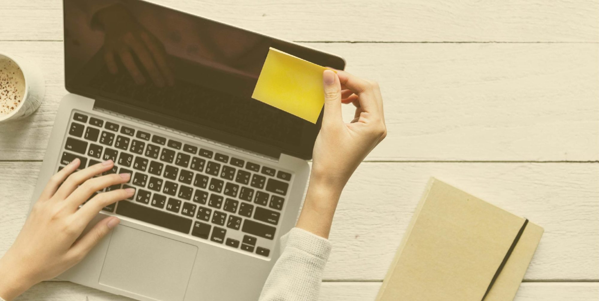 An image of someone putting a yellow sticky note onto a computer.