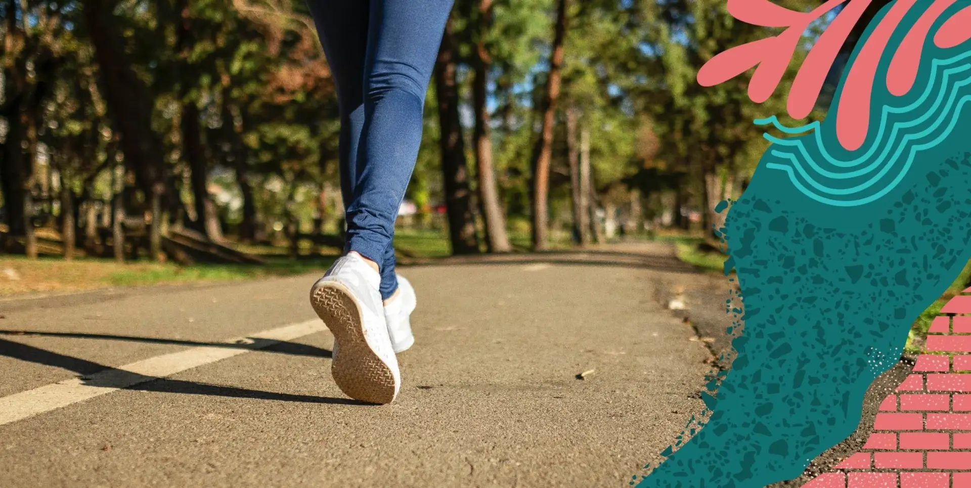 Someone in jeans and sneakers running down a paved and wooded trail.