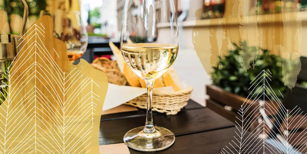 A winge glass on a table with bread in the background.