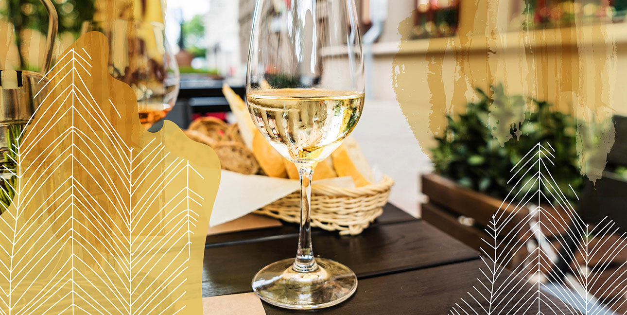 A winge glass on a table with bread in the background.