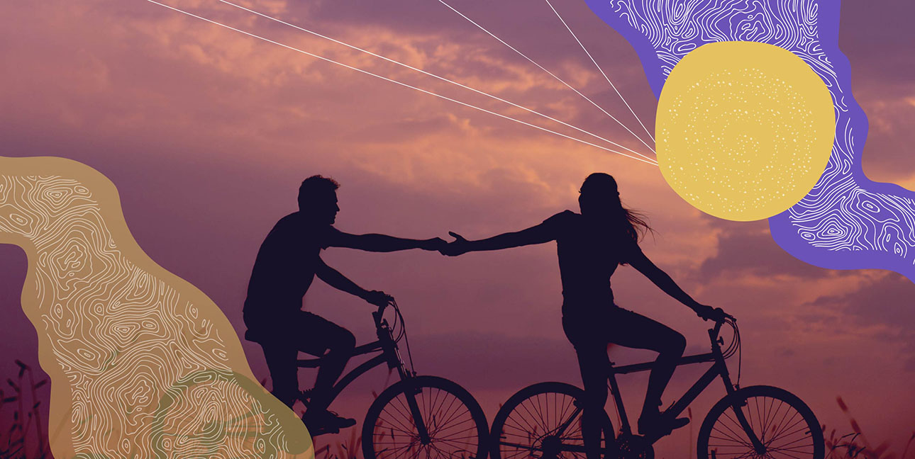 A couple riding their bike along a beach at sunset.