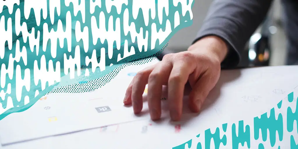 A person's hand on top of a stack of designs.