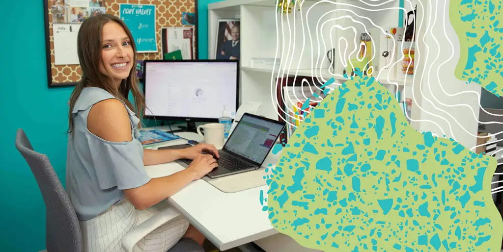 A woman sitting at her desk, typing on a laptop