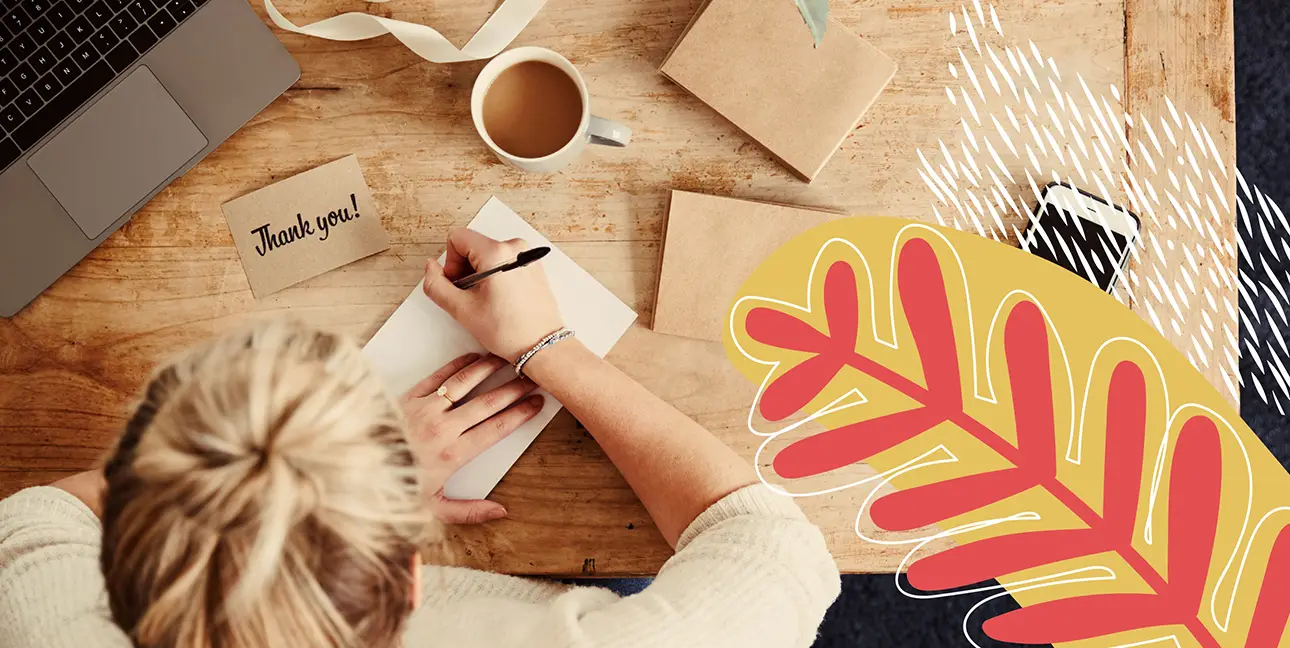 A person hand writing a thank you note.
