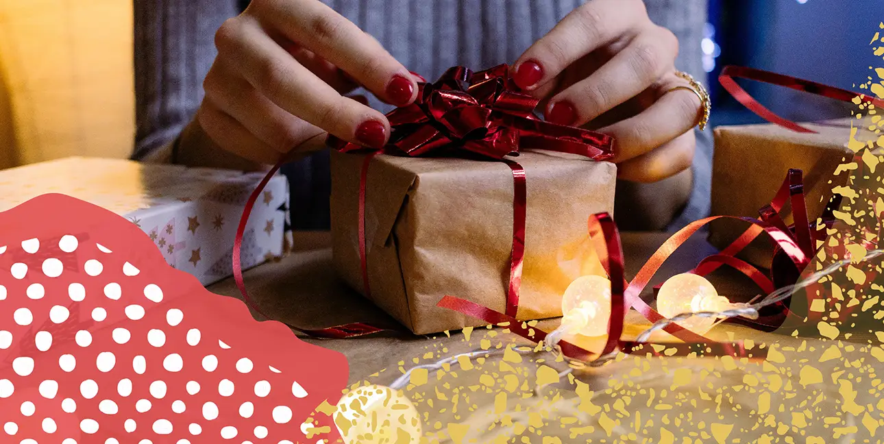 a pair of hands wrapping a bow around a gift