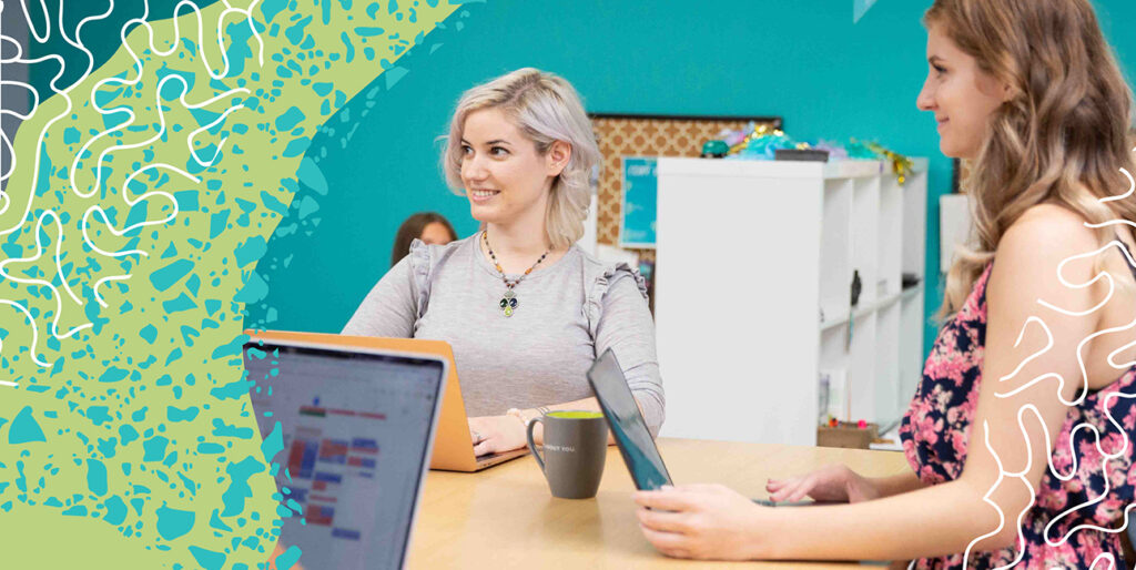 two coworkers standing around a table in a meeting