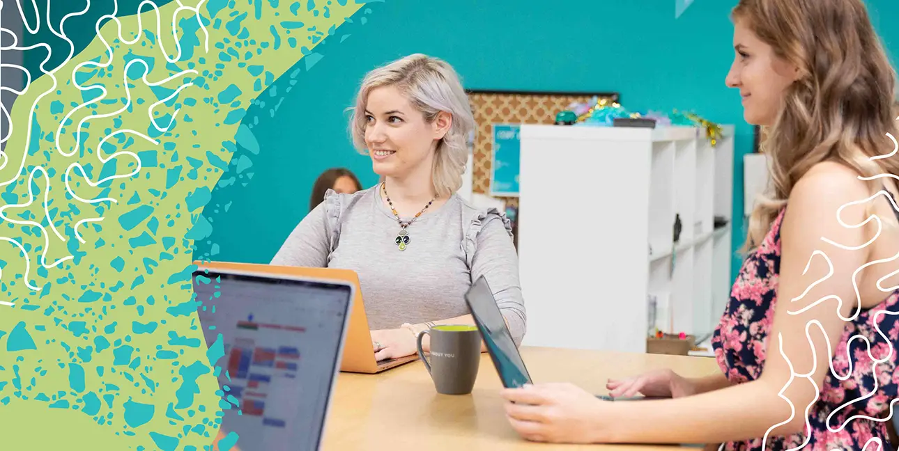 two coworkers standing around a table in a meeting