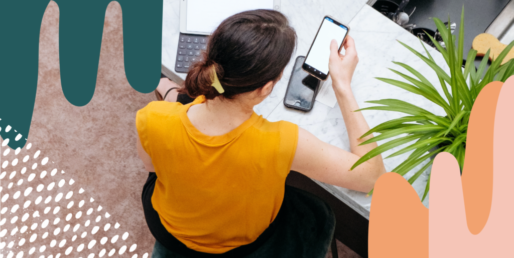 woman wearing a yellow shirt checking phone and computer