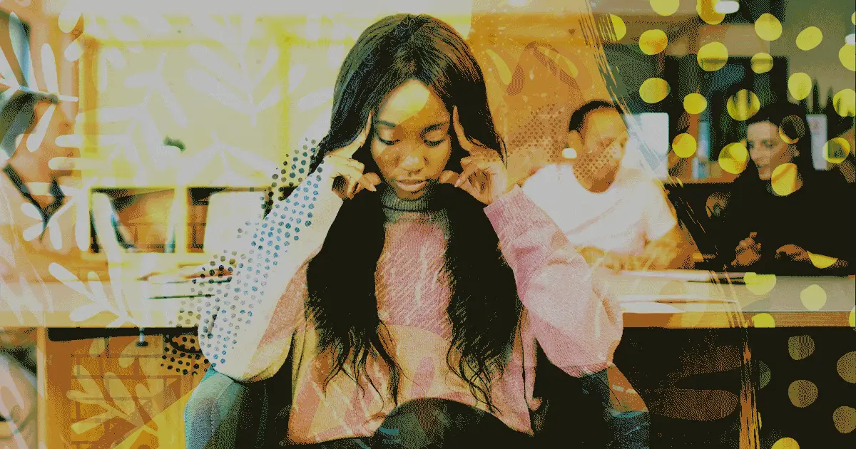 Woman with hands on her head with people walking behind her