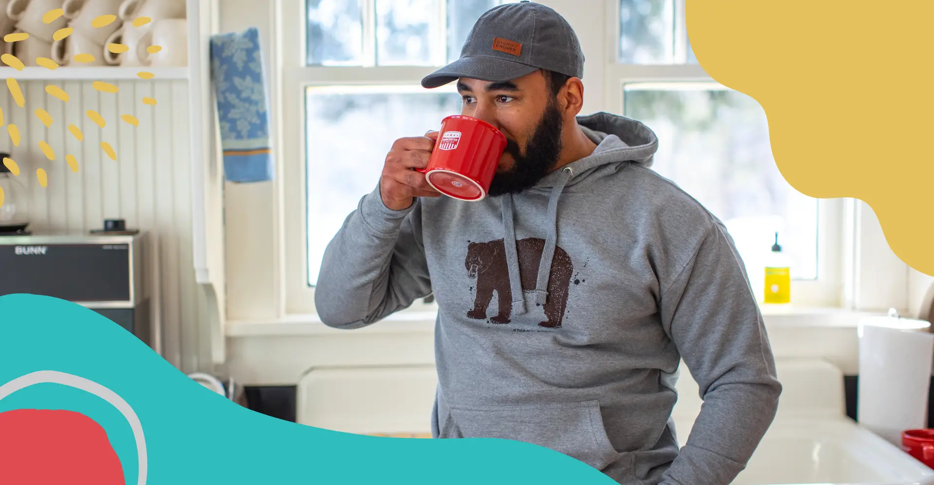 Guy drinking coffee in kitchen wearing Stormy Kromer cap
